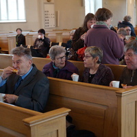 Kirkkovieraita istumassa Tyrvään kirkon penkeillä ja juomassa kahvia.