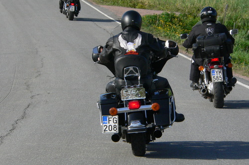 Kolme moottoripyöräilijää ajaa tietä pitkin eteenpäin.