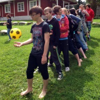 Jono nuoria seuraa kärjessä olevaa nuorta, joka heittelee jalkapalloa ilmaan.