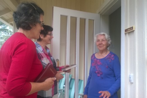 Kaksi Virrenviejää vierailemassa vanhemman naisen ovella..