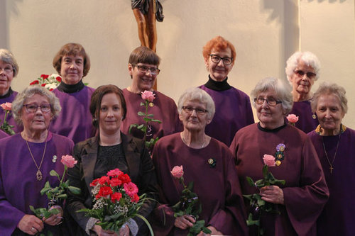 Karkun kirkkokuoro kukkia käsissään ryhmäkuvassa.