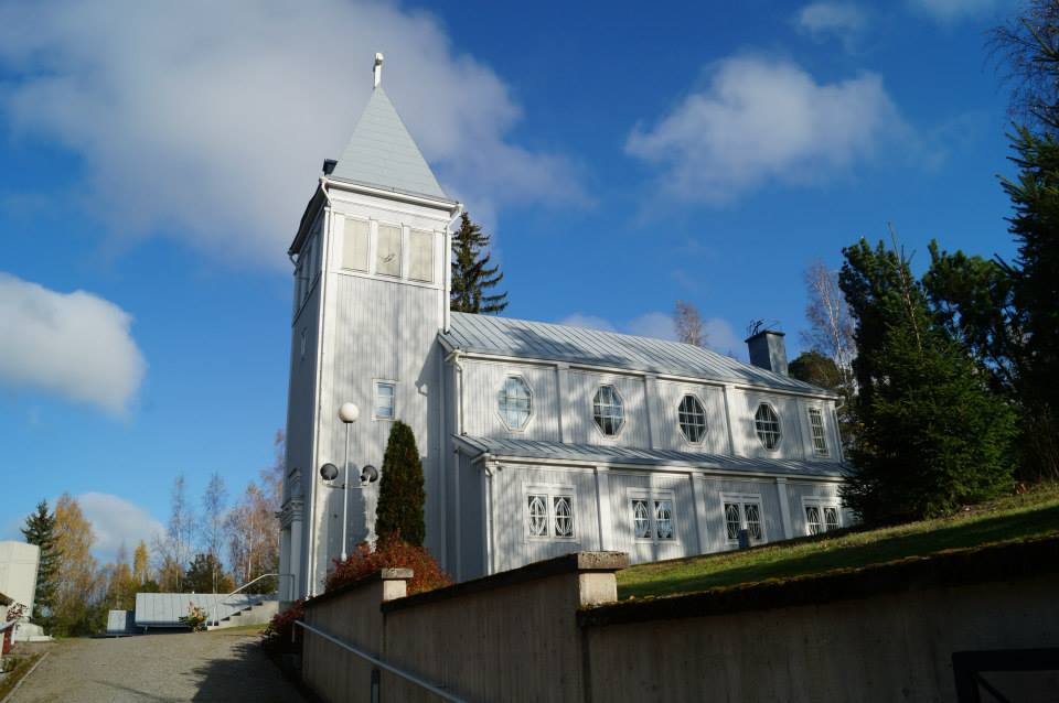 Sammaljoen kirkko sivusta kuvattuna puolipilvisenä päivänä, torni vasemmalla puolella.